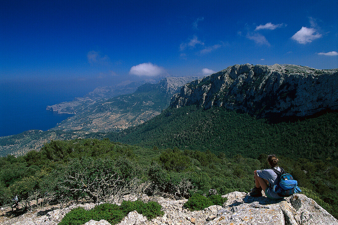 Woman sitting on rock, looking at view, Serra de Tramuntana, Majorca, Spain