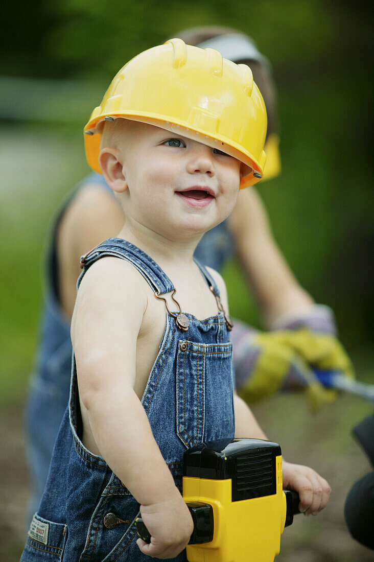 Boy 3-4 years, wearing hard hat holiding toy jackhammer, Styria, Austria