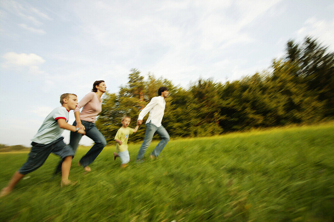 Family running through green meadow