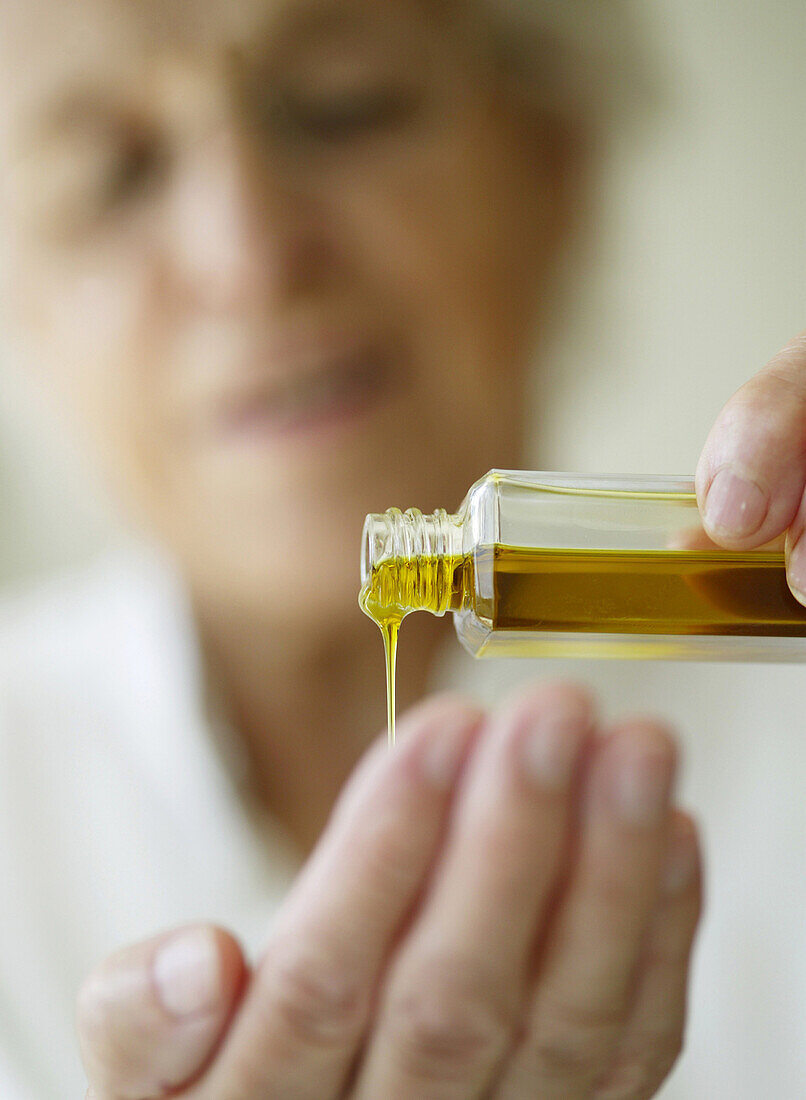 Woman pouring massage oil in hand, Vienna, Austria