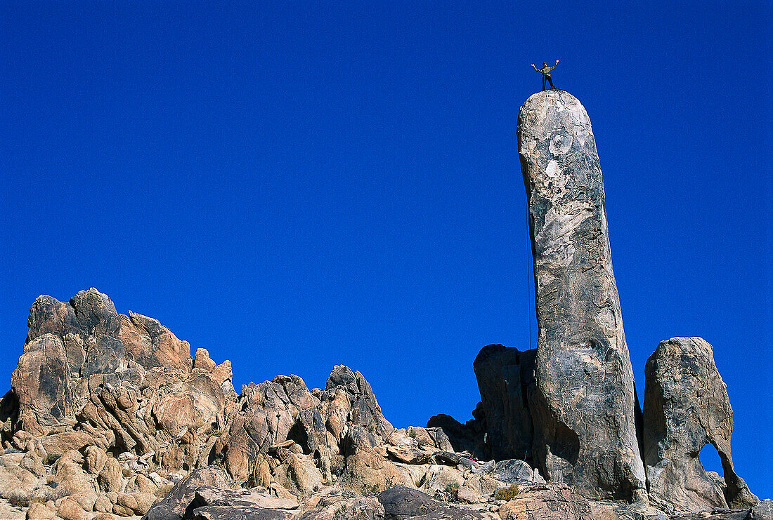 Climber on top of the Hercules Finger rock, High Desert, California, USA