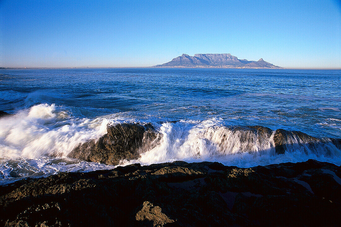 Coastal landscap, waves crashing against rocks, Bloubergstrand, Table Mountain in the background, Cape Town, South Africa