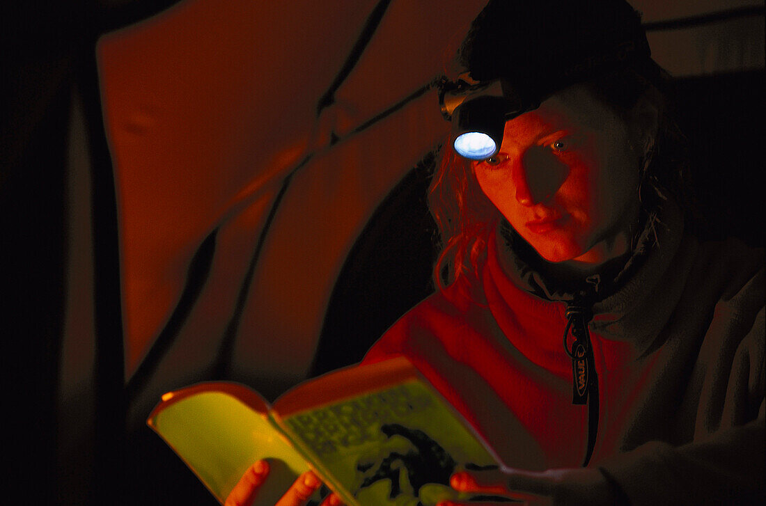 Frau liest ein Buch mit Taschenlampe, Camping, Südafrika