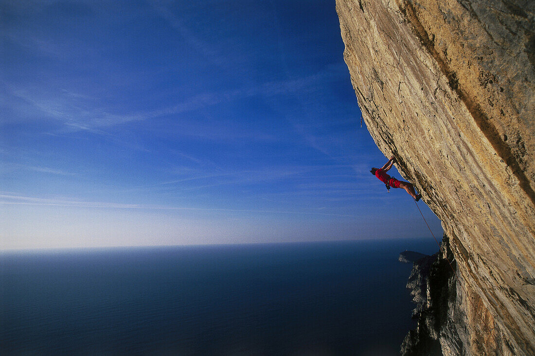 Male free climber scaling rock face, No Siesta 8b, Muzzerone, Portovenere, Cinque Terre, Liguria, Italy