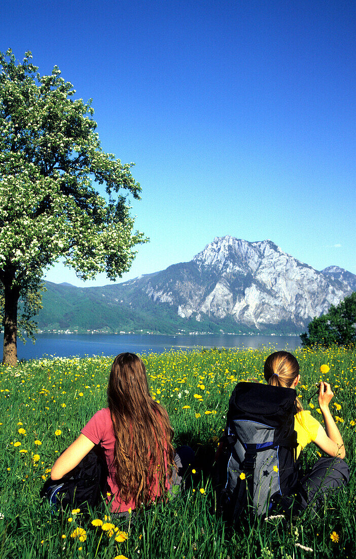 Girls having a rest in a field of flowers, Traun Lake, Traunstein Mountains, Salzkammergut, Austria