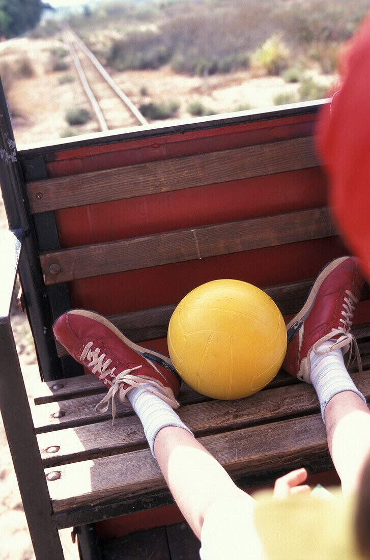 Boy sitting feet up in small train, Parque Natural da Ria Formosa , Tavira, Algarve, Portugal