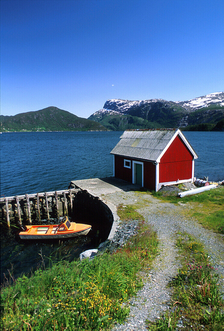 Timber house and jetty at a fjord in the sunlight, Sogn og Fjordane, Norway, Europe