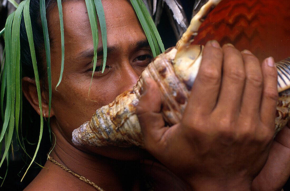 Polynesier blaest auf Muschel, trad. Instru., Kopfschmuck-Tiki Village Insel Moorea, Franz. Polynesien