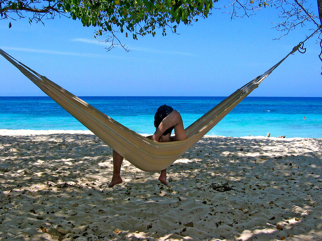 Mann liegt auf einer Hängematte mit Blick aufs Meer, Carribbean Beach, Cartagena, Kolumbien, Südamerika