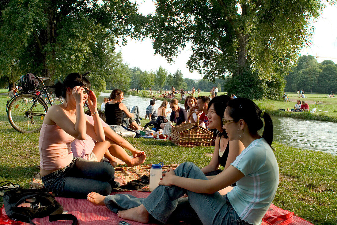 Young women in front of Eisbach, picnic, English Garden, Munich, Bavaria, Germany