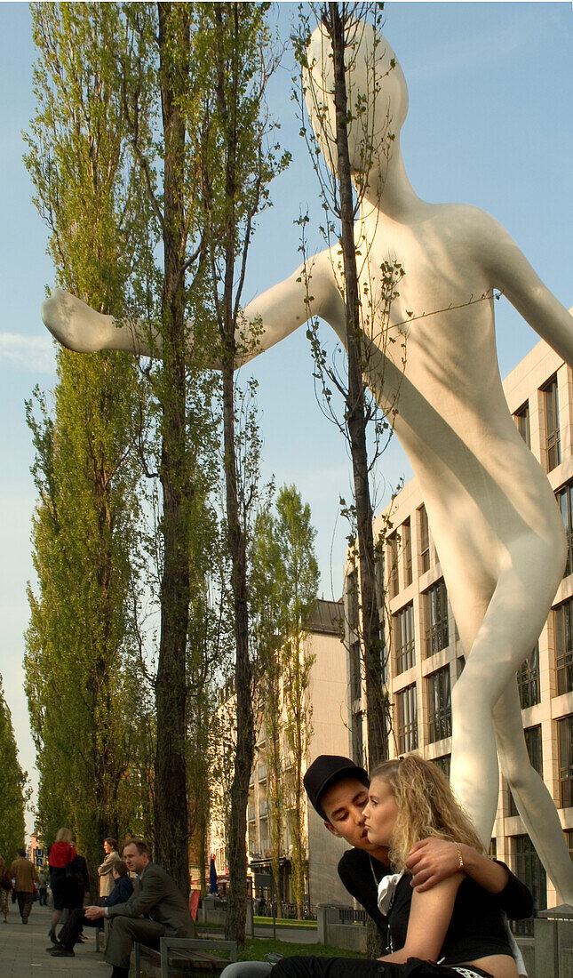 Couple in front of Walking Man sculpture, Leopoldstrasse, Schwabing, Munich, Bavaria, Germany
