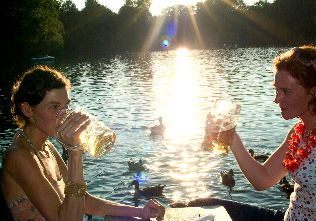 Young women toasting with beer steins, Seehaus Beergarden, English Garden, Munich, Bavaria, Germany
