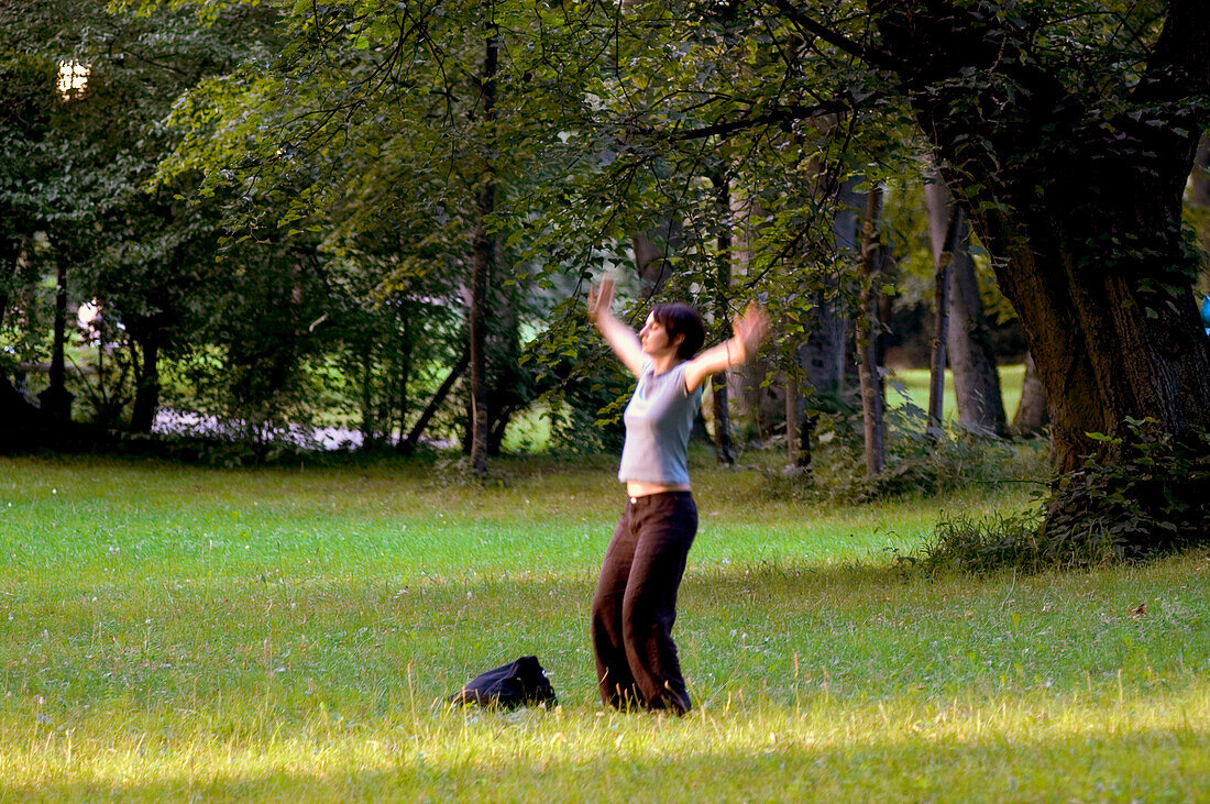 Woman exercising Tai Chi in Park next to Isar, Munich, Bavaria, Germany