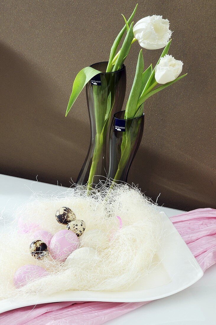 Easter eggs in white straw and tulips in a vase