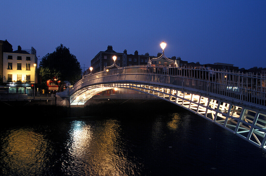 The illuminated Halfpenny Bridge above the river Liffey at night, Dublin Ireland, Europe