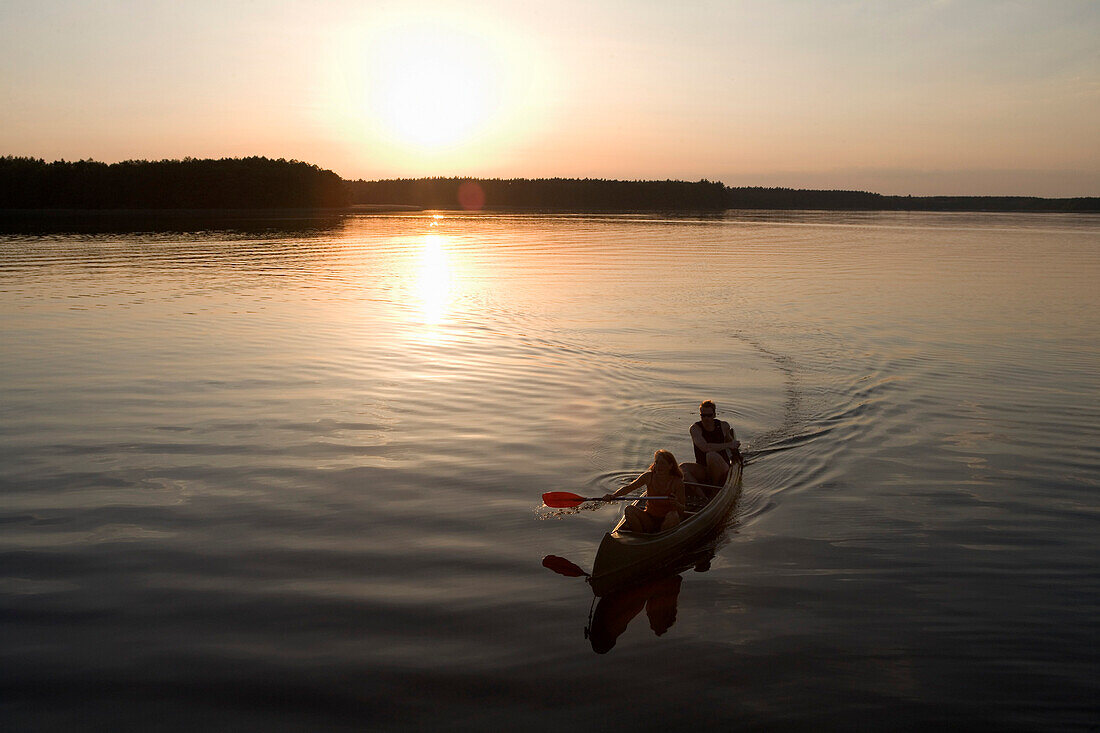 Couple canoeing at sunset, Zotzensee, Mecklenburgian Lake District, Germany