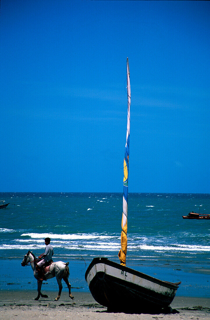 Ein Reiter neben Jangada, Jericoacoara, Ceara, Brasilien