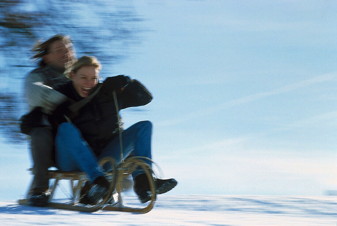 Young couple sledding downhill