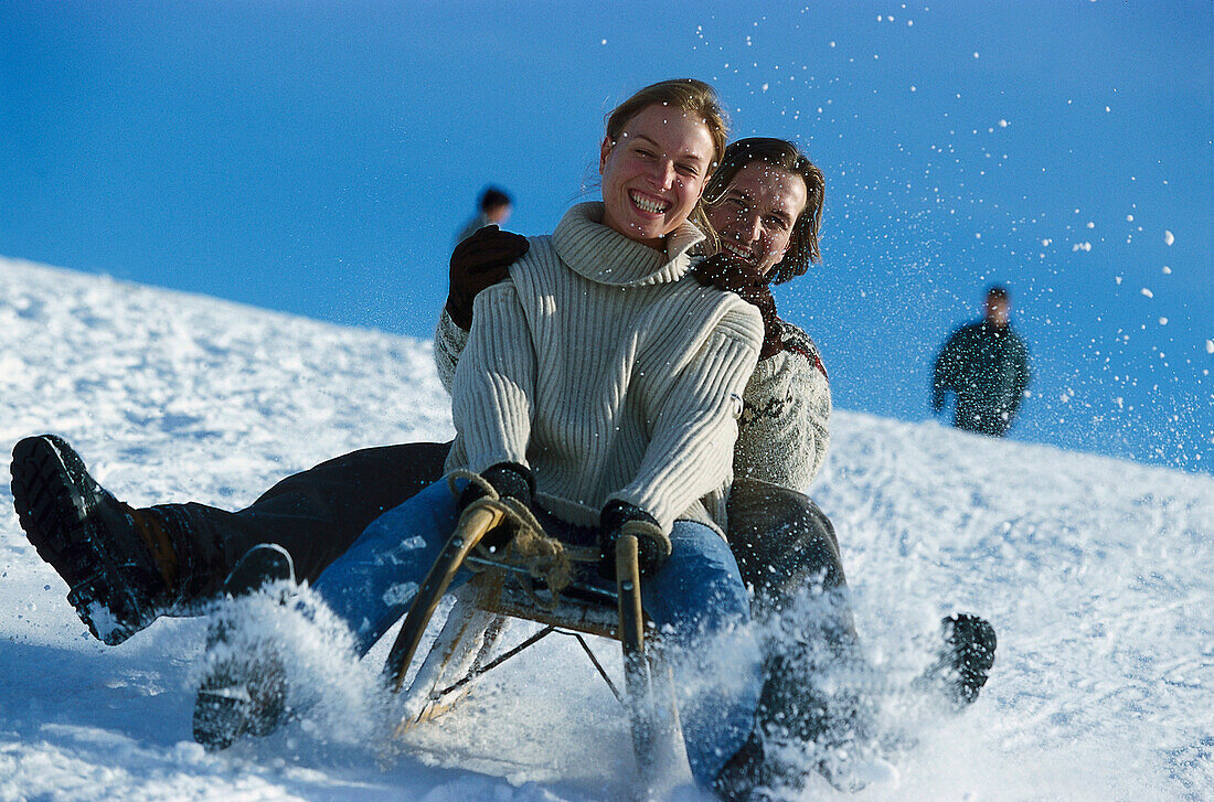 Young couple sledging down a slope, Winter sport