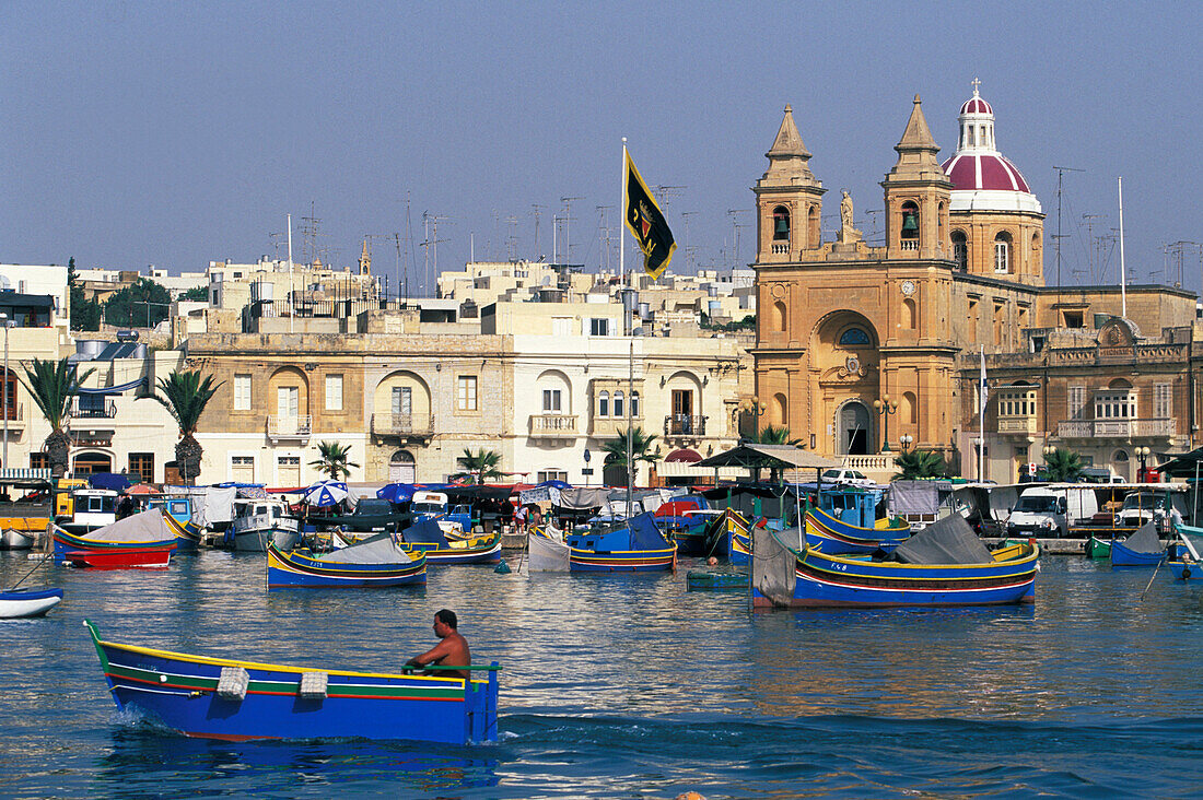 View of fishing boats at harbour and church, Marsaxlokk, Malta, Europe