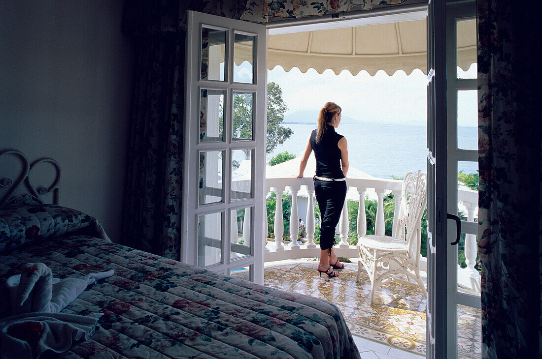 Woman looking out from the balcony of her hotel room at La Puntilla De Piergiorgio Palace Hotel, Sosua, Dominican Republic, Caribbean