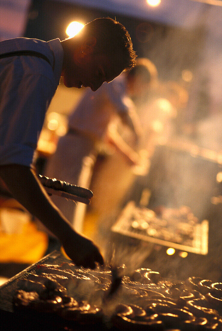 Mann grillt Wurste, Barbecue, Bayern, Deutschland