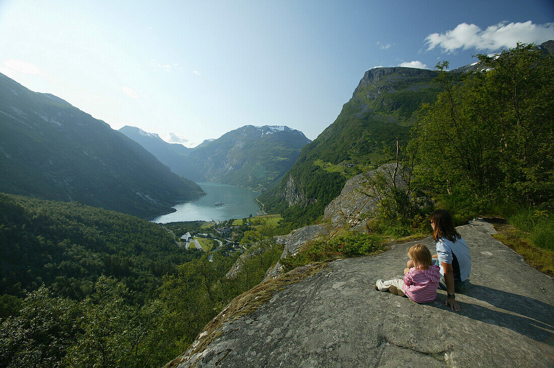 Mother with daughter sitting on the rocks above Geiranger Fjord, More og Romsdal, Norway