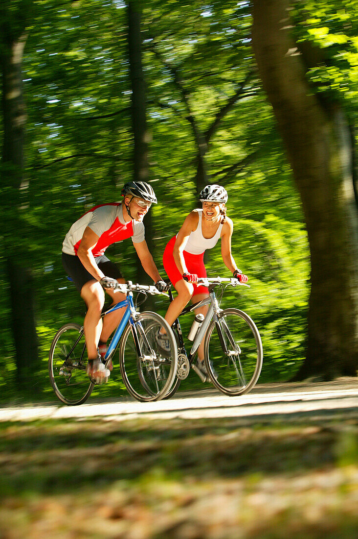 Couple riding fitness bicycles on forest track, Bavaria, Germany