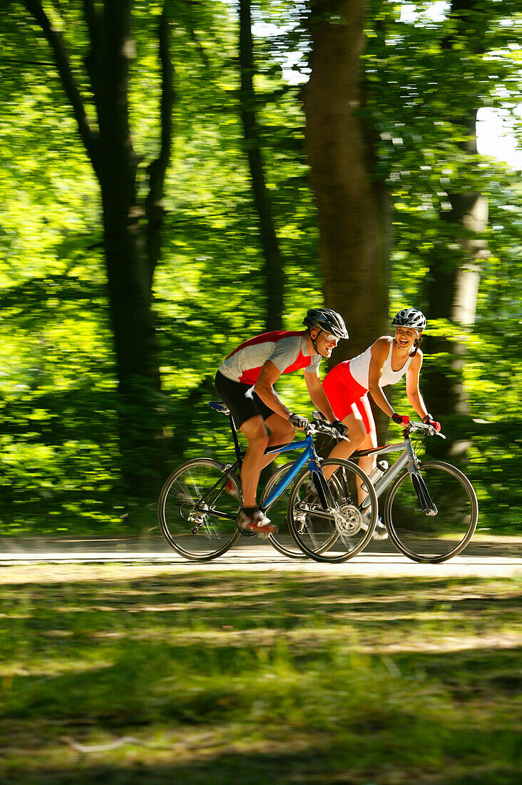 Couple riding fitness bicycles on forest track, Bavaria, Germany