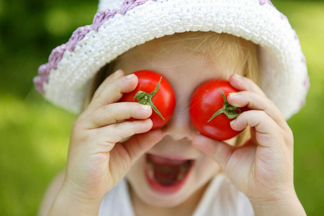 Young girl with tomatos on her eyes, garden