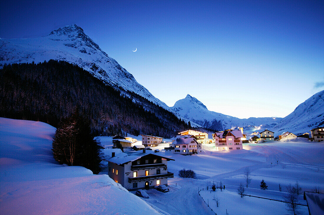 Blick über verschneites Bergdorf in der Dämmerung, Tirol, Österreich