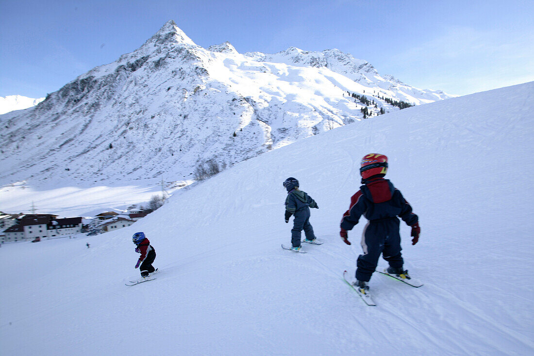 Drei kleine Kinder beim Skifahrer, Skischule, Wirl in der Nähe von Galtuer, Gorfenspitze im Hintergrund, Wirl in der Nähe von Galtuer, Tirol, Austria