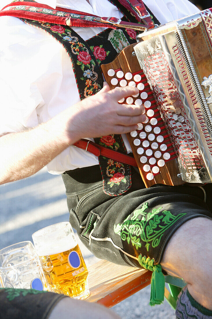 Man wearing traditional leather trousers playing accordion, Garmisch Partenkirchen, Bavaria, Germany