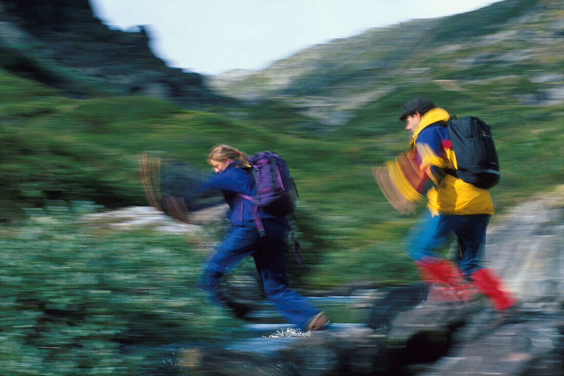 Young couple crossing stream, Dumdalen, Jotumheimen NP Norway