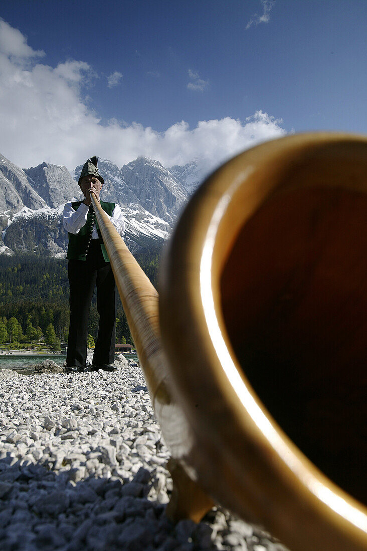 Alphornbläser am Ufer des Eibsee, Zugspitze im Hintergrund, Bayern, Deutschland