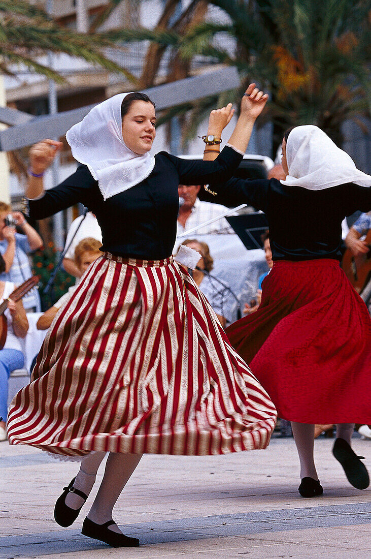 Two young girls in traditinal costume dancing to folklore music, Majorca, Spain