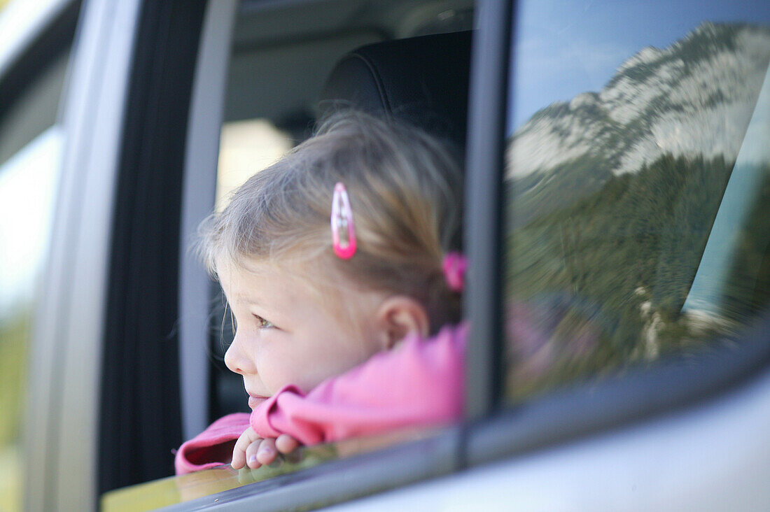 Young girl looking out the car window, Young girl looking out of the car window, Alpenstrasse, Reiteralpe, Ramsau, Germany, Junges Maedchen blickt aus Autofenster, Alpenstrasse, Spiegelung Reiteralpe, Ramsau, D