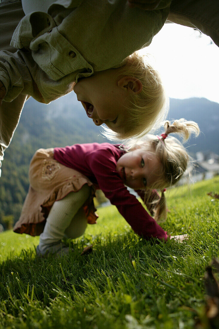 Father playing with children on meadow, St Bartholoma, Konigssee, Berchtesgadener Land, Bavaria, Germany