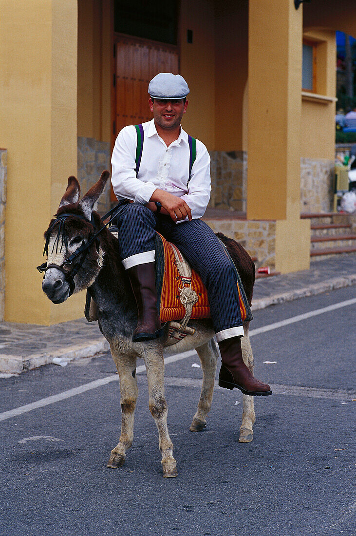 Pilgrim riding a donkey on a street, Romeria de San Isidro, Nerja, Costa del Sol, Malaga province, Andalusia, Spain, Europe