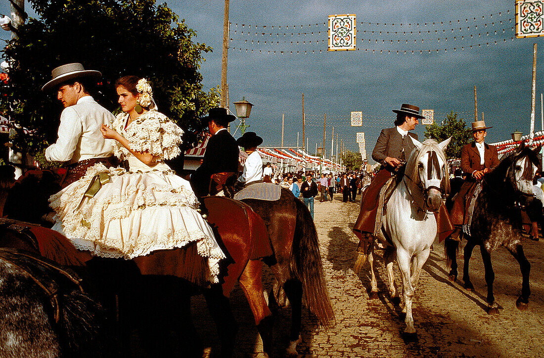 Menschen in Tracht zu Pferde unter Gewitterwolken, Feria de Abril, Sevilla, Andalusien, Spanien, Europa