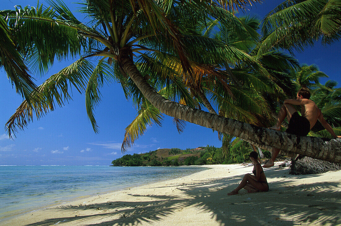 Couple sitting on the beach in the shade, Ile aux Nattes, Ste Marie, Madagascar, Indian Ocean