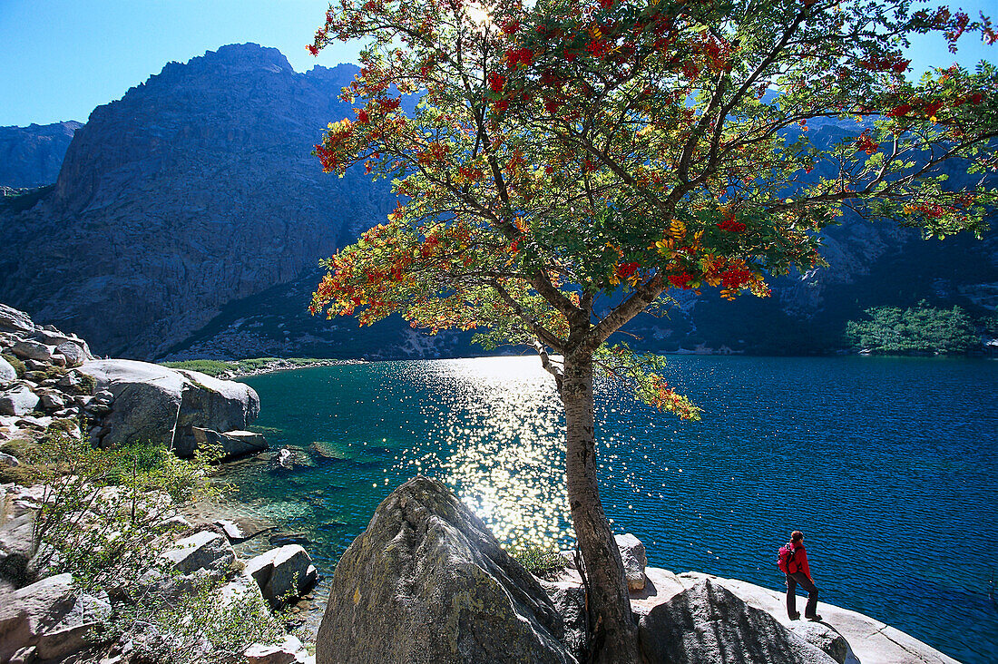 Woman standing on lakeshore, Lac de Melo, Corsica, France