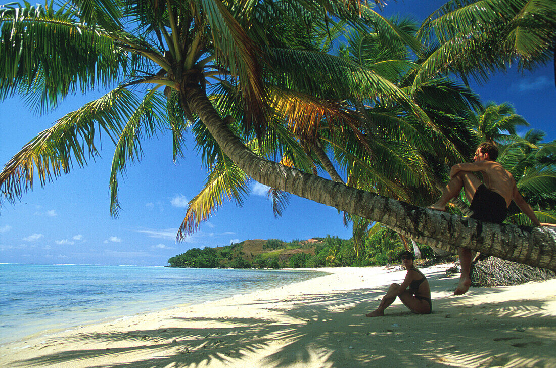 Couple sitting on the beach in the shade, Ile aux Nattes, Ste Marie, Madagascar, Indian Ocean