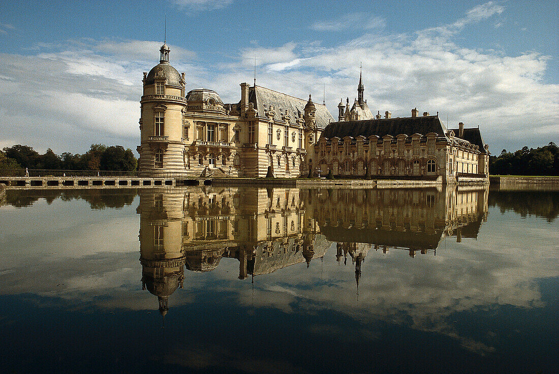 The castle Chateau de Chantilly and reflection in a lake, Ile de France France, Europe