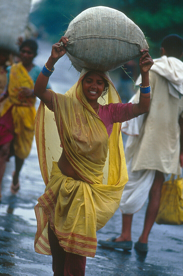Laughing woman carrying a sack, Muzaffarpur, Bihar, India, Asia