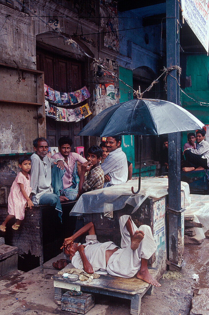 Market stall, man under umbrella, monsoon, Varanasi, Benares, Uttar Pradesh, India