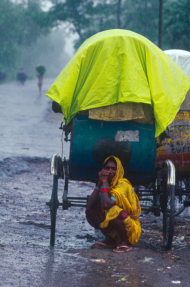 Frau steht bei Rikscha unter, Monsun, Muzaffarpur, Bihar, Indien