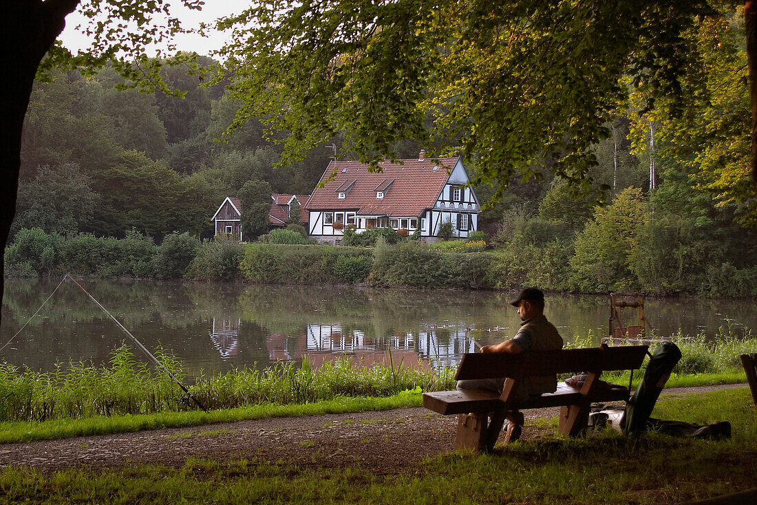 Angler sitzt auf einer Bank, Horn Bad-Meinberg, Nordrhein-Westfalen, Deutschland