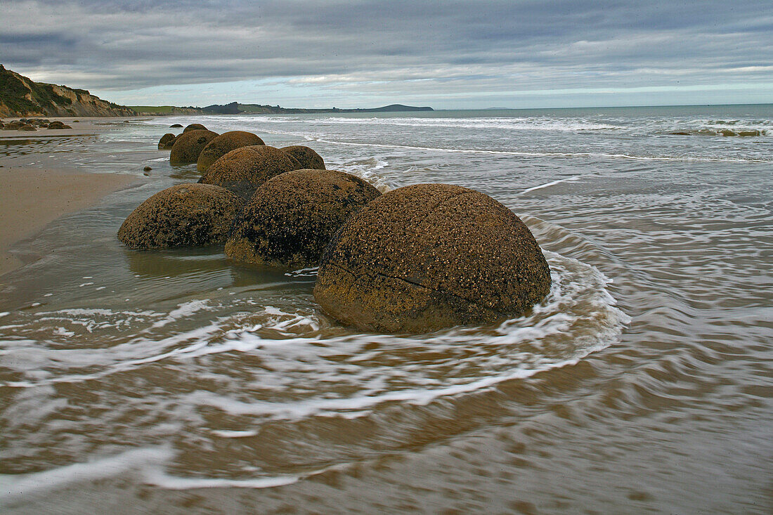 Moeraki Felsbrocken am Strand unter Wolkenhimmel, Südinsel, Neuseeland, Ozeanien