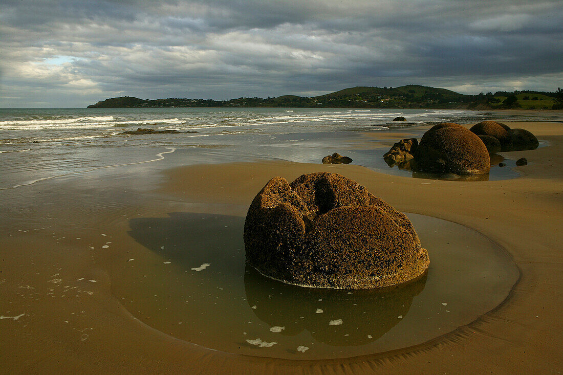 Moeraki Felsbrocken am Strand unter Wolkenhimmel, Südinsel, Neuseeland, Ozeanien